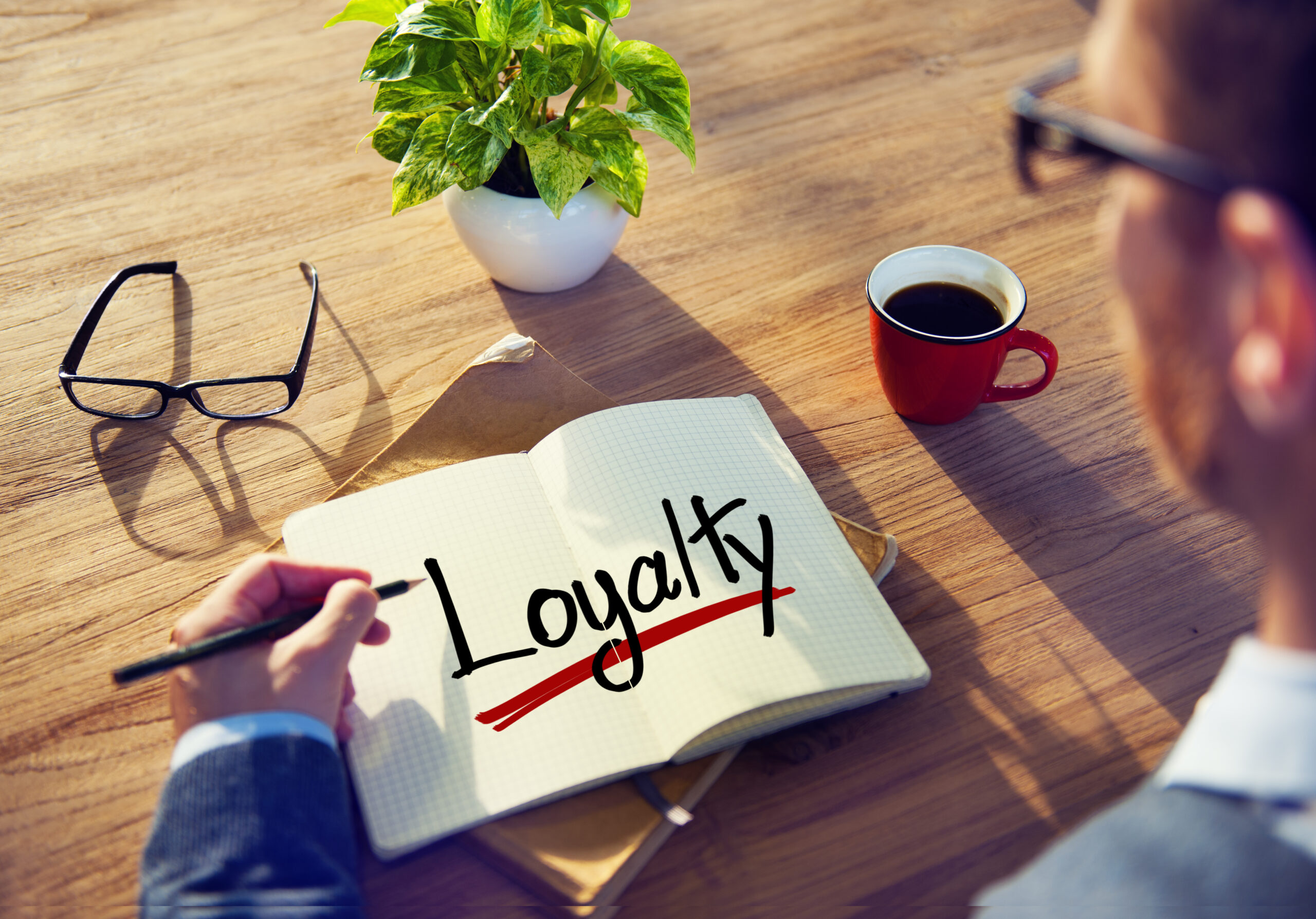 A man jotting down ‘loyalty’ as a key focus for customer loyalty campaigns.
